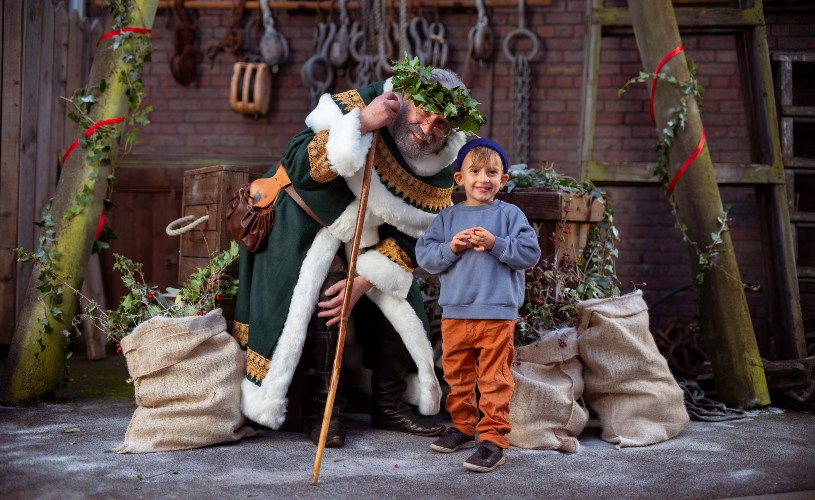 Old Father Christmas in Victorian green robes with little boy at SS Great Britain